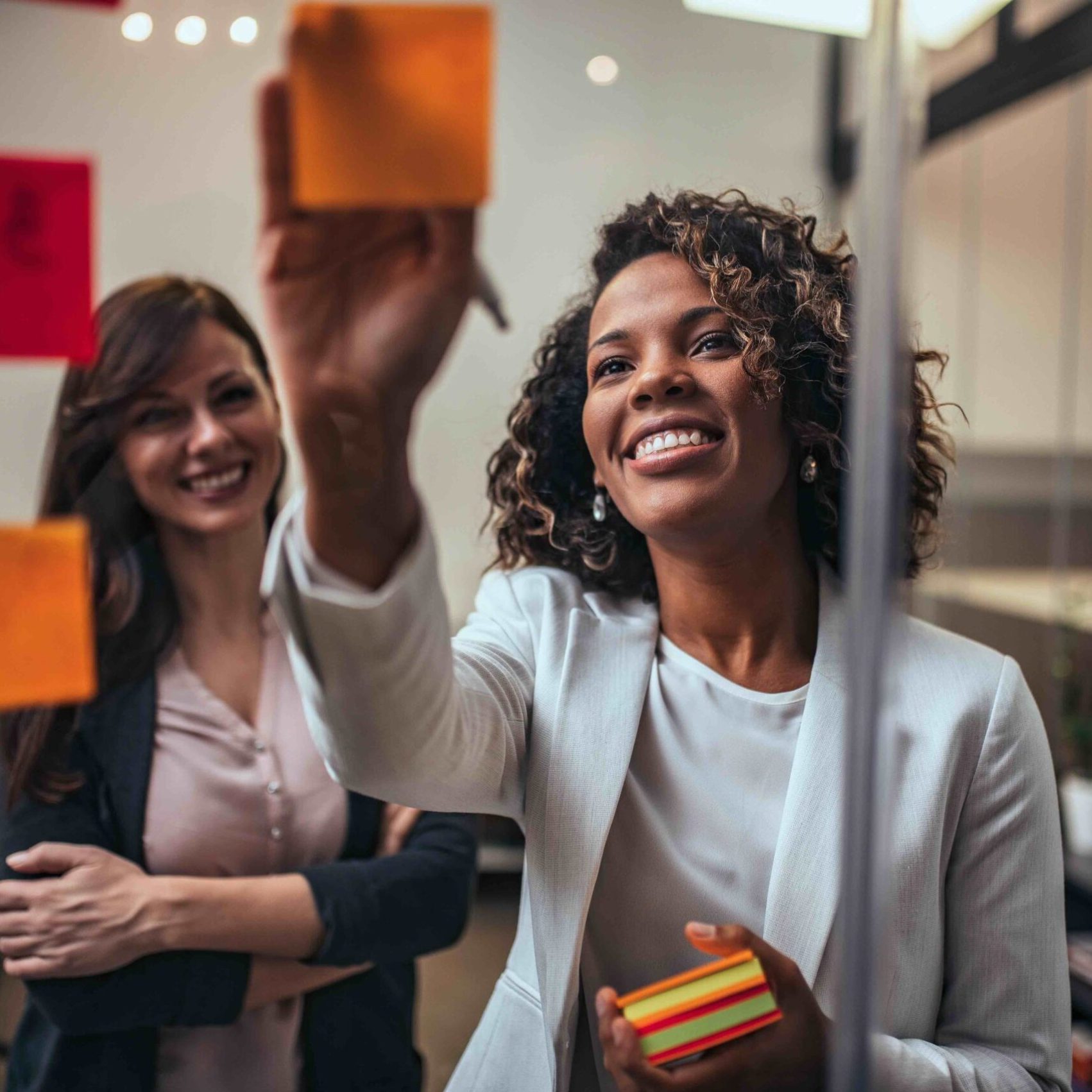 Two creative small business owners working on strategy using adhesive notes, portrait. Two creative small business owners working on strategy using adhesive notes, portrait.